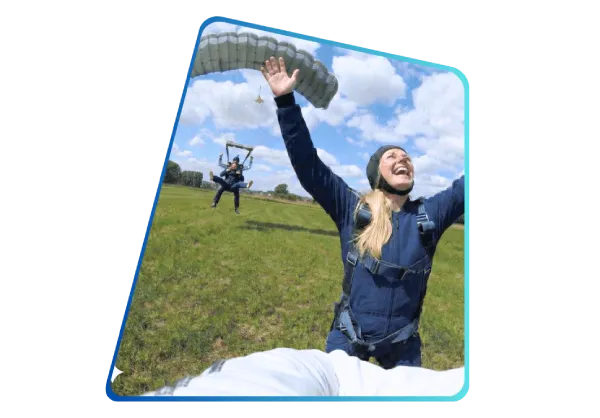 Landung nach dem Tandemfallschirmsprung. Zufriedene Frau freut sich über Tandemsprung.